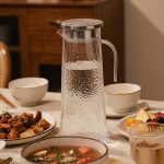 BY-9168 unbreakable PC stainless steel handle water pitcher (steel) - set on a dining table for dinner