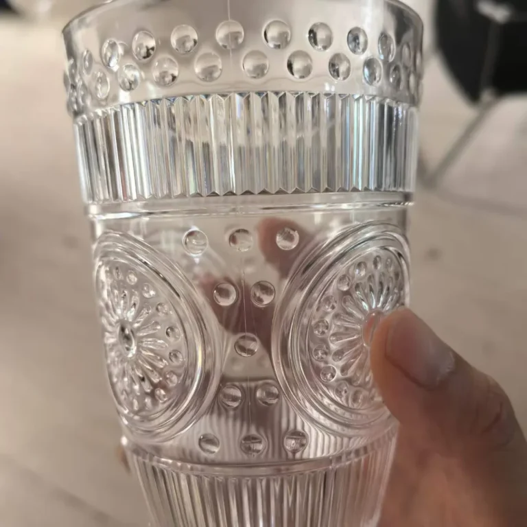 Retro embossed unbreakable polycarbonate tumbler with beaded band, fluted wall and sunflower rosette, held in hand, hotel drinkware by Benyang Supplies