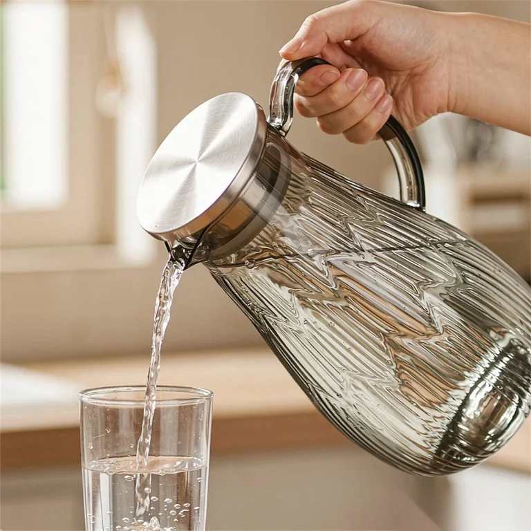 Clear unbreakable PC water jug with a stainless steel lid pouring water into a glass tumbler, part of the hotel water pitcher range from Benyang Supplies